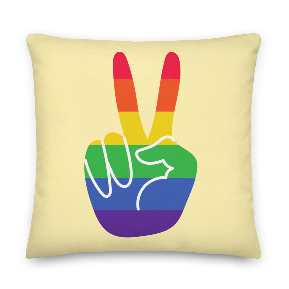 Pale yellow square pillow with a rainbow-striped hand making a V sign