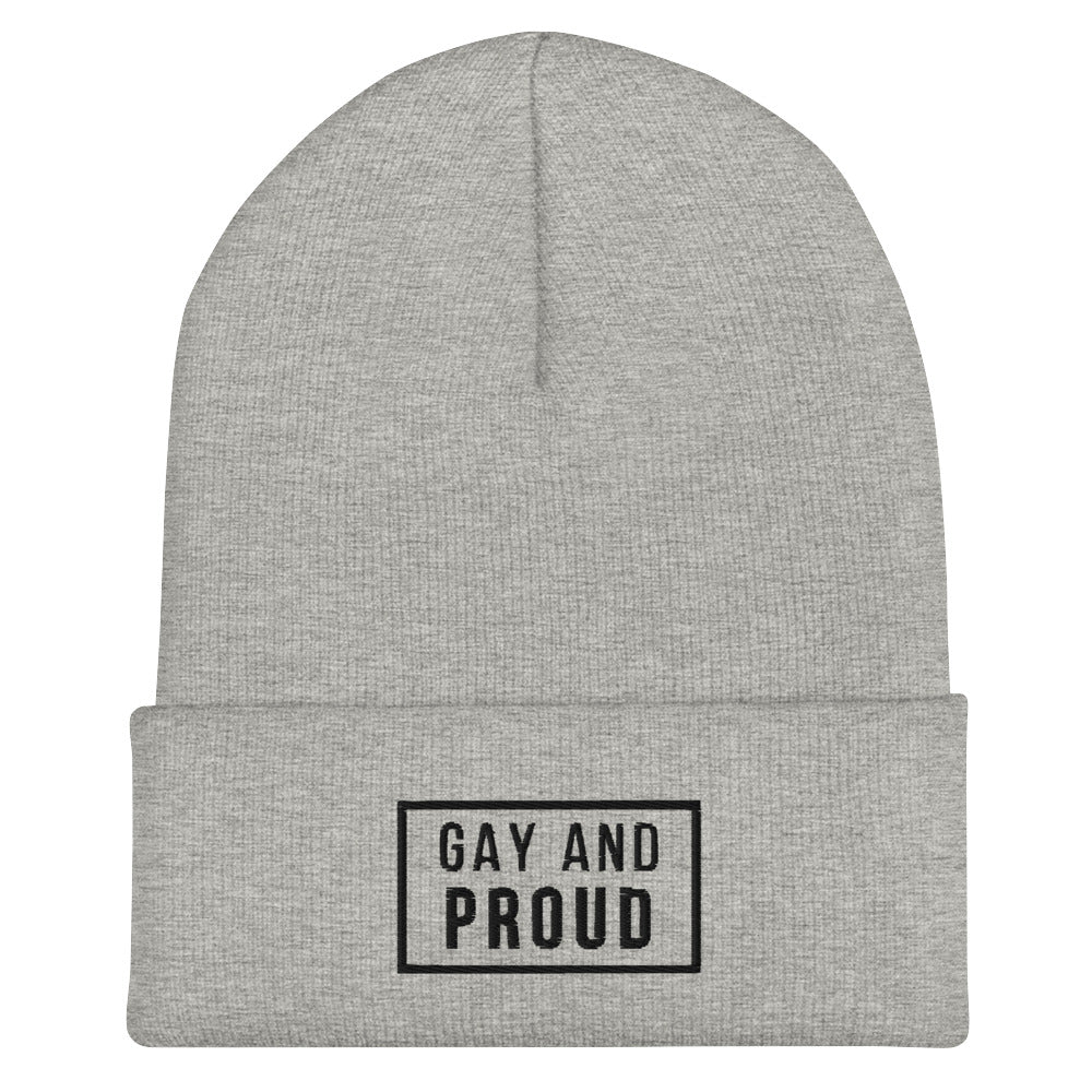 Front view of a heather-gray cuffed beanie reading “GAY AND PROUD” in a black-outlined patch.