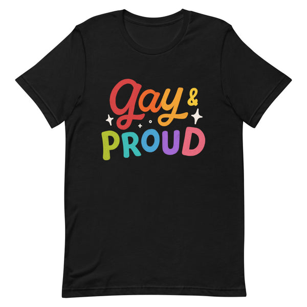 Black “Gay & Proud” T-shirt with big rainbow lettering, folded on a white bed next to two phones and an open book; unisex pride gear.