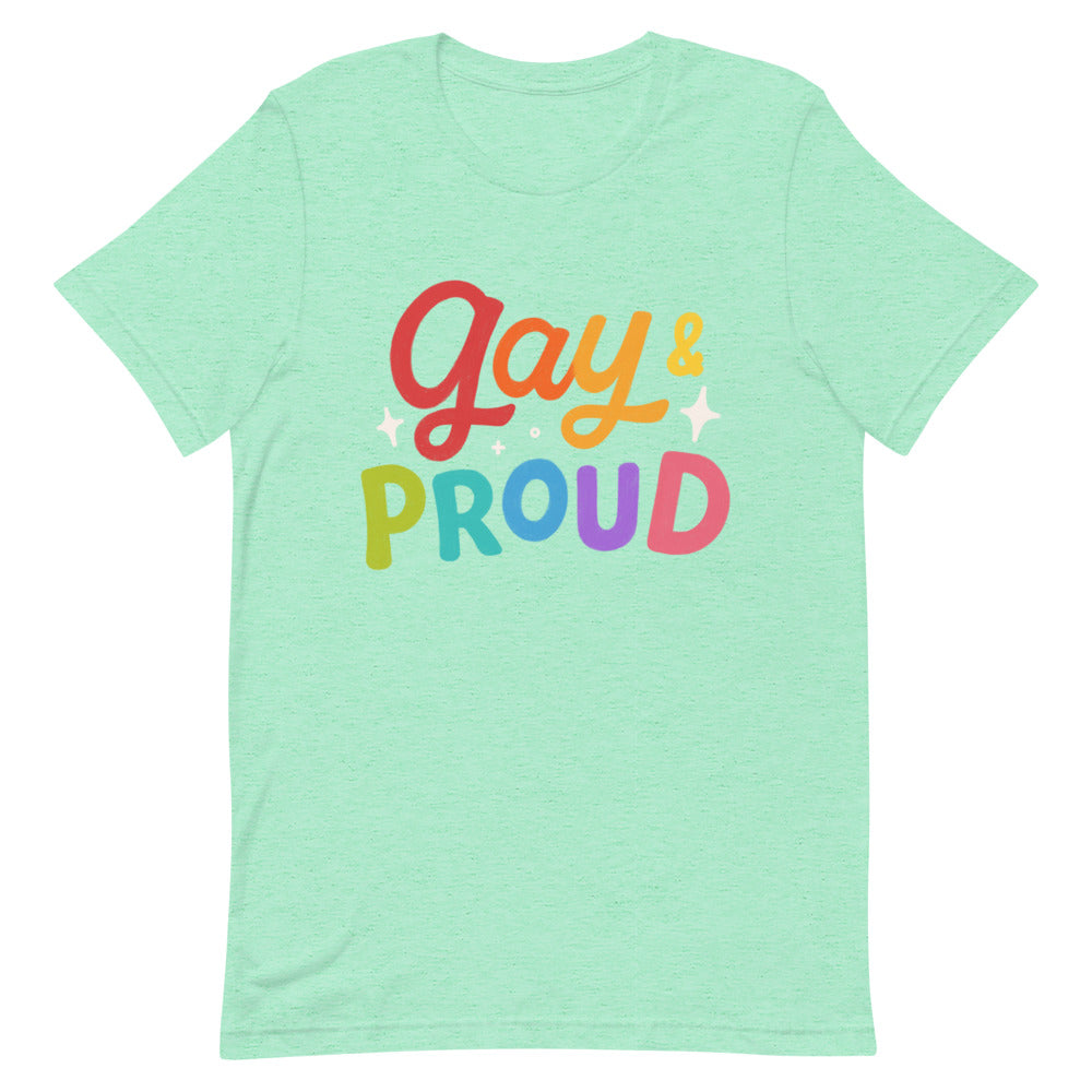 Unisex mint green cotton tee with rainbow "gay & PROUD" text, pride colors shining. Only lower face shown, soft minimal wall backdrop.