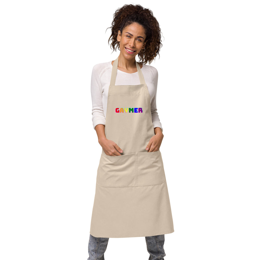 Front view of a beige apron worn by a smiling model, with colorful “GAYMER” lettering and a large pocket
