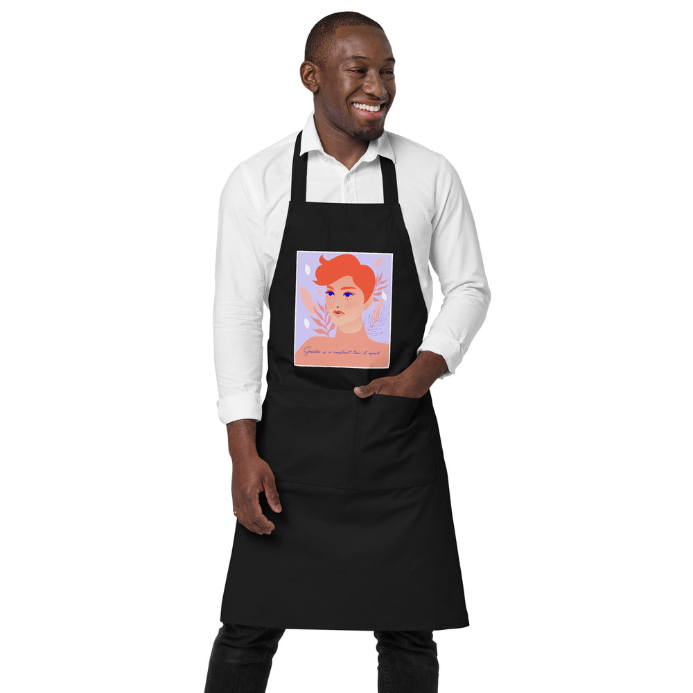 Model wearing a black apron with a colorful portrait and “Gender is a construct tear it apart” text