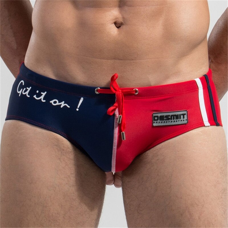 Front close-up of a person wearing navy and red low-rise swim briefs with drawstring