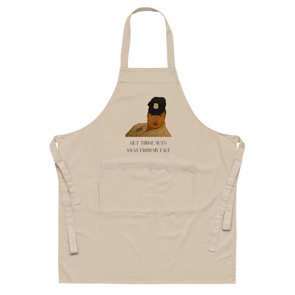 Beige apron with neck strap, waist ties, front pocket, cartoon portrait, and “GET THOSE NUTS AWAY FROM MY FACE” text