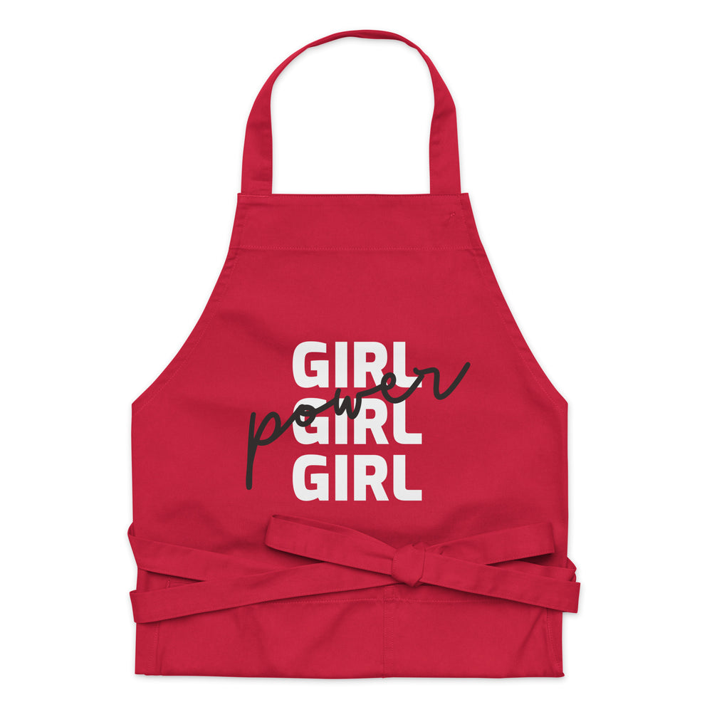 Front view of a red apron reading “GIRL GIRL GIRL” with black script overlay and waist ties