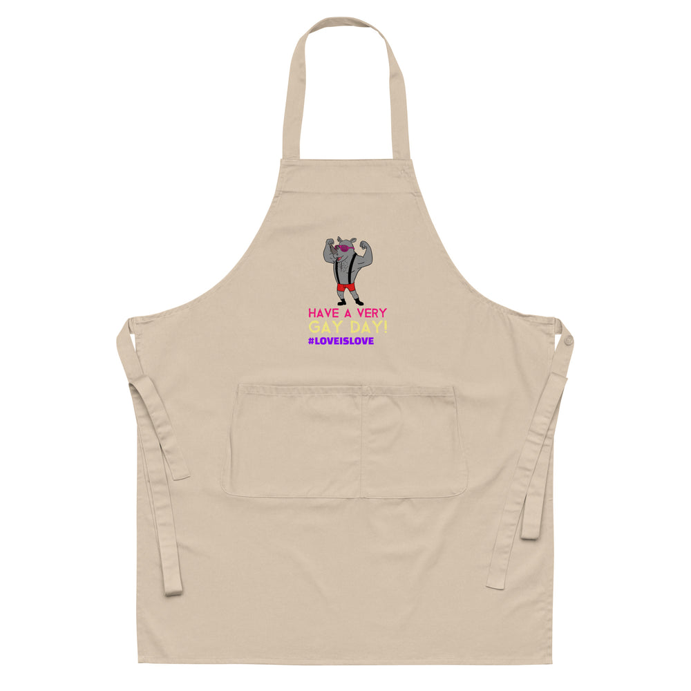 Beige apron with a flexing cartoon figure and “HAVE A VERY GAY DAY! #LOVEISLOVE” text
