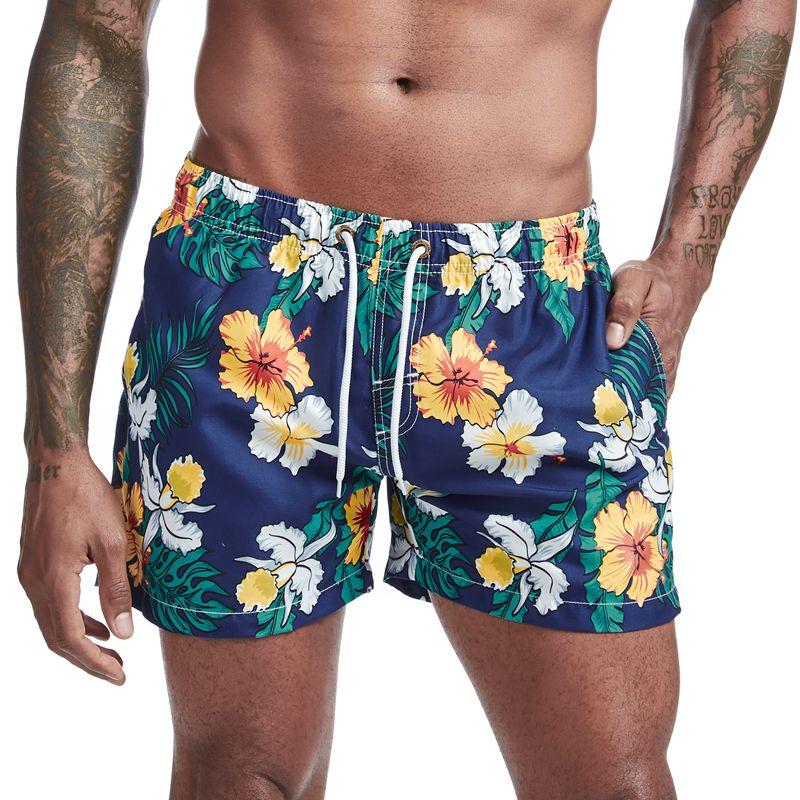 Close-up of navy floral board shorts with yellow and white hibiscus flowers, drawstring waist, and pockets