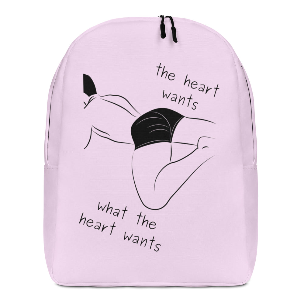 Front view of a pale pink backpack with a black abstract figure and “the heart wants what the heart wants”