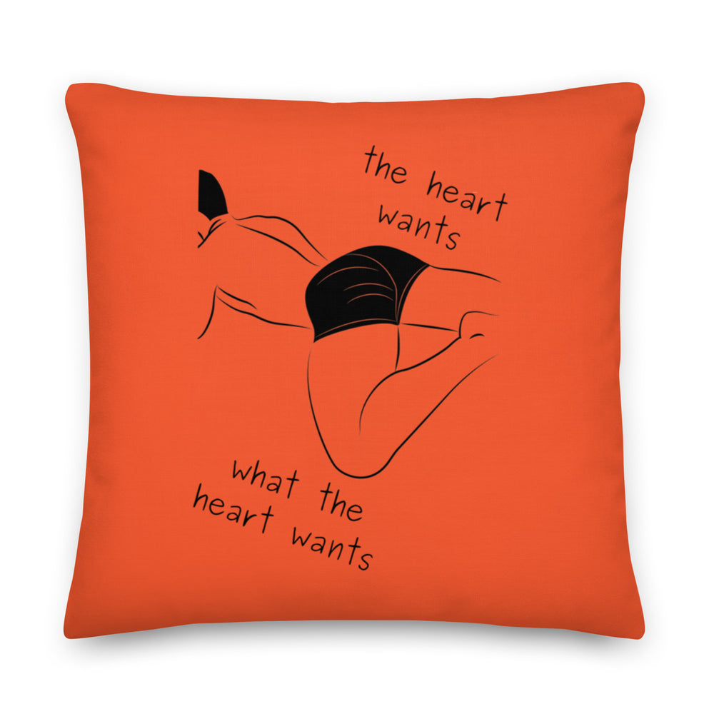 Orange square pillow with a black reclining figure and the words “the heart wants what the heart wants”