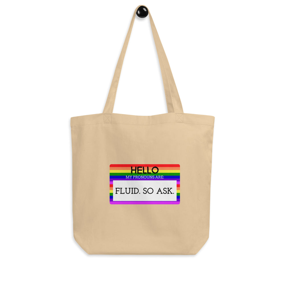 Front-facing beige tote bag with a rainbow-bordered sign reading “HELLO MY PRONOUNS ARE: FLUID. SO ASK.”