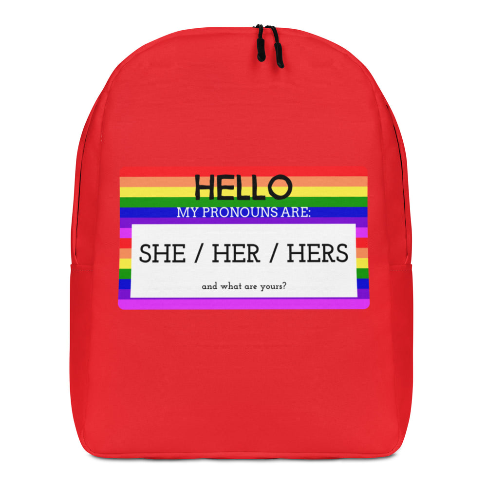 Front view of a red backpack with a rainbow-striped pronoun design reading “HELLO MY PRONOUNS ARE: SHE / HER / HERS.”