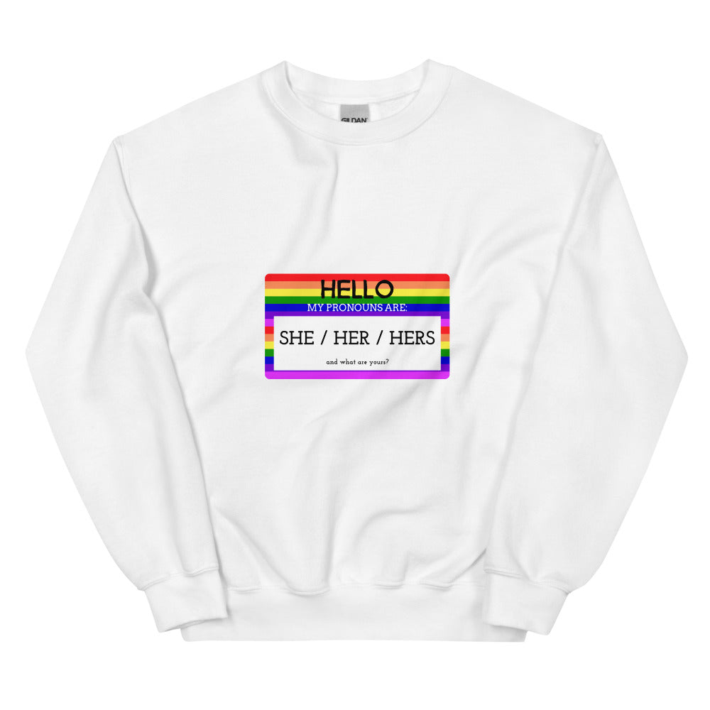 Front view of a white sweatshirt with a rainbow pronoun badge reading “HELLO” and “SHE / HER / HERS.”