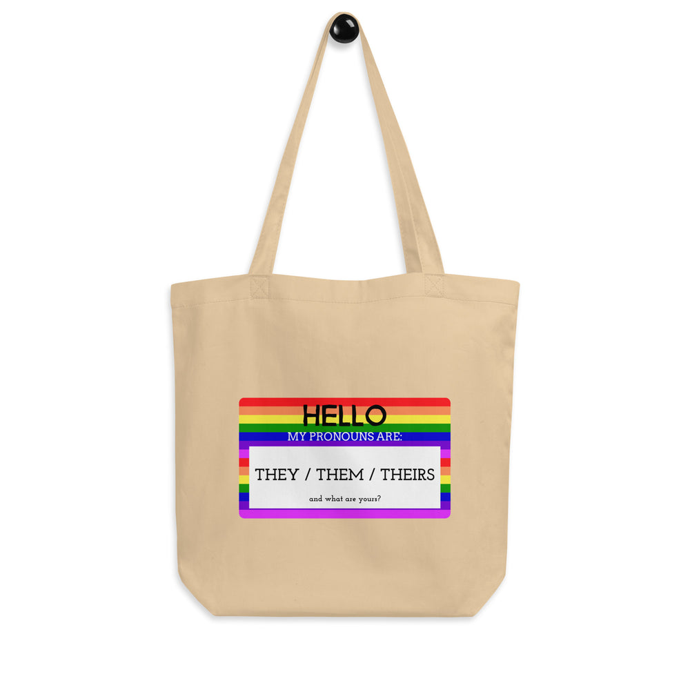 Natural canvas tote with a rainbow label reading “Hello, my pronouns are: they / them / theirs.”