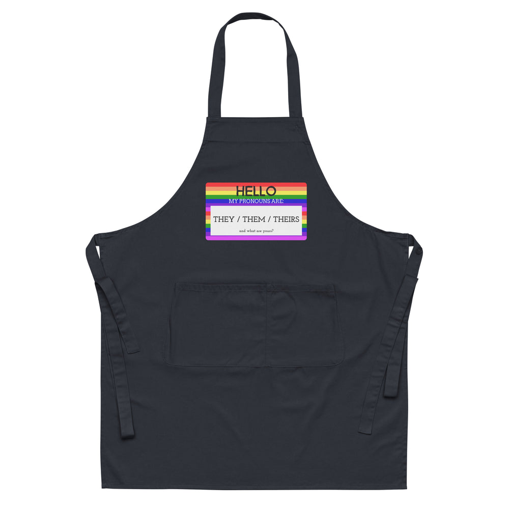 Front-facing black apron with rainbow-bordered sign reading “HELLO MY PRONOUNS ARE: THEY / THEM / THEIRS.”