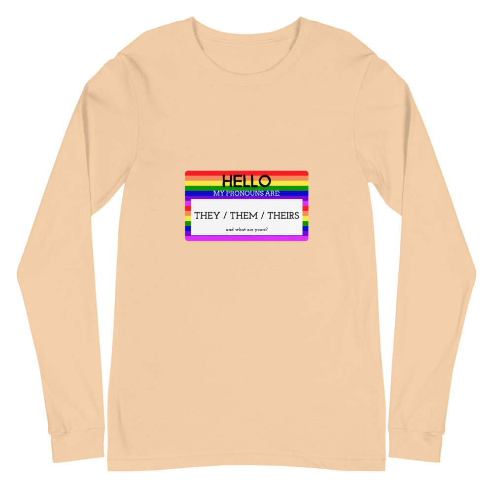 Front view of a sand-colored long-sleeve shirt with a rainbow pronoun badge reading “THEY / THEM / THEIRS.”