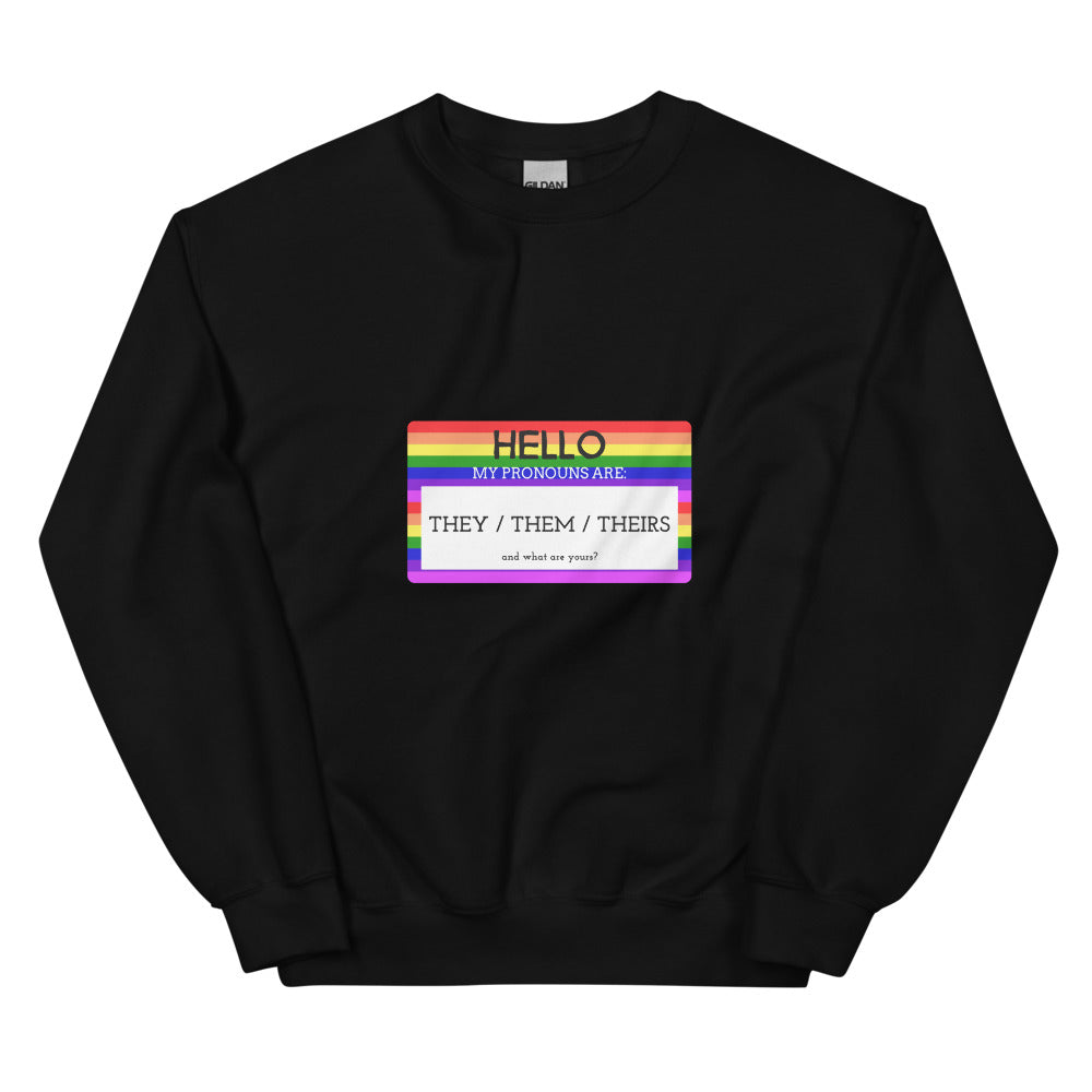 Front view of a black sweatshirt with a rainbow pronoun badge reading “THEY / THEM / THEIRS.”