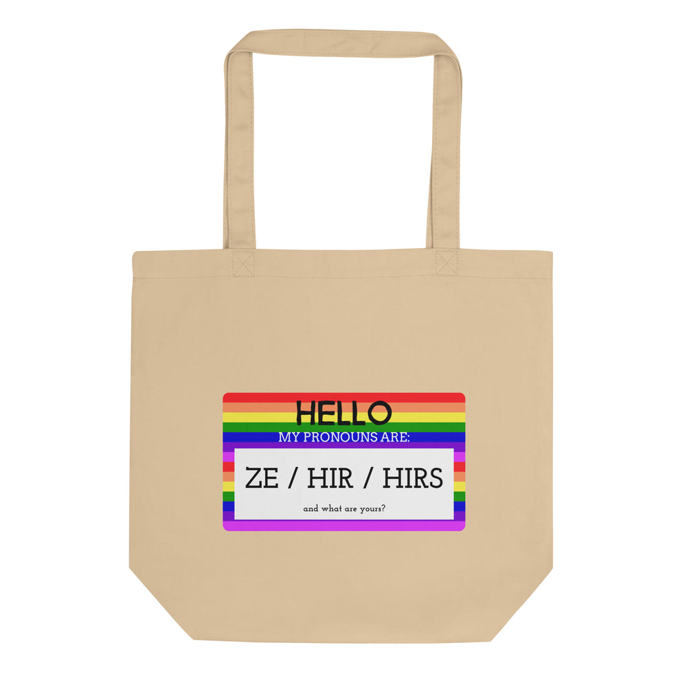 Front-facing beige tote bag with rainbow panel reading “HELLO, MY PRONOUNS ARE: ZE / HIR / HIRS.”