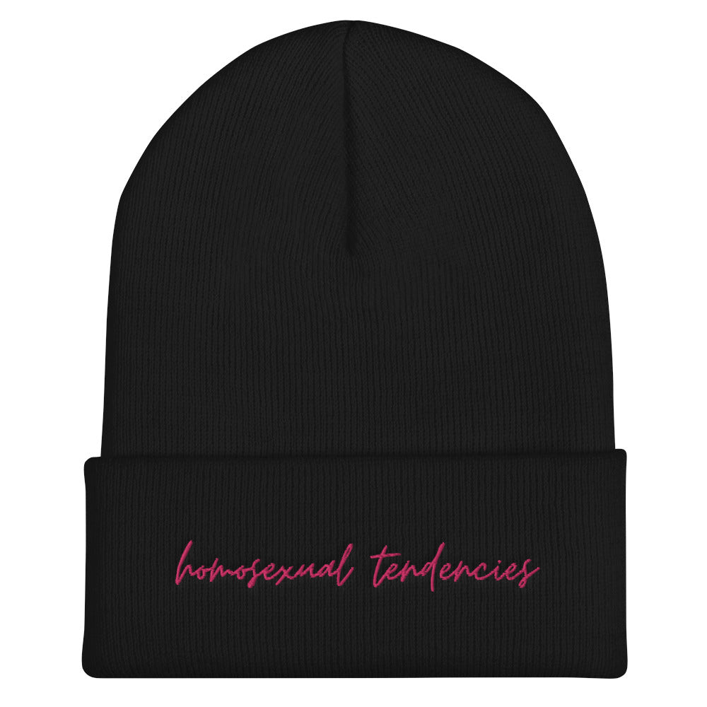 Front view of a black cuffed beanie with pink cursive text, “homosexual tendencies”
