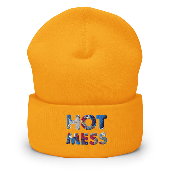 Front view of an orange cuffed beanie embroidered with “HOT MESS” in multicolored thread.