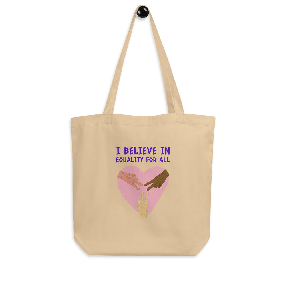Natural canvas tote bag reading “I BELIEVE IN EQUALITY FOR ALL,” with a pink heart and three hands