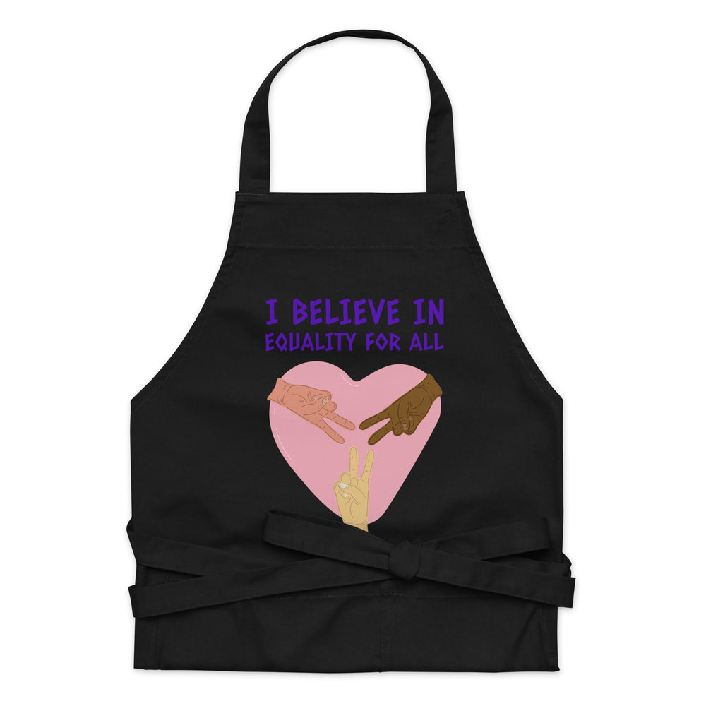 Black apron with purple “I BELIEVE IN EQUALITY FOR ALL” text and heart-shaped hands graphic