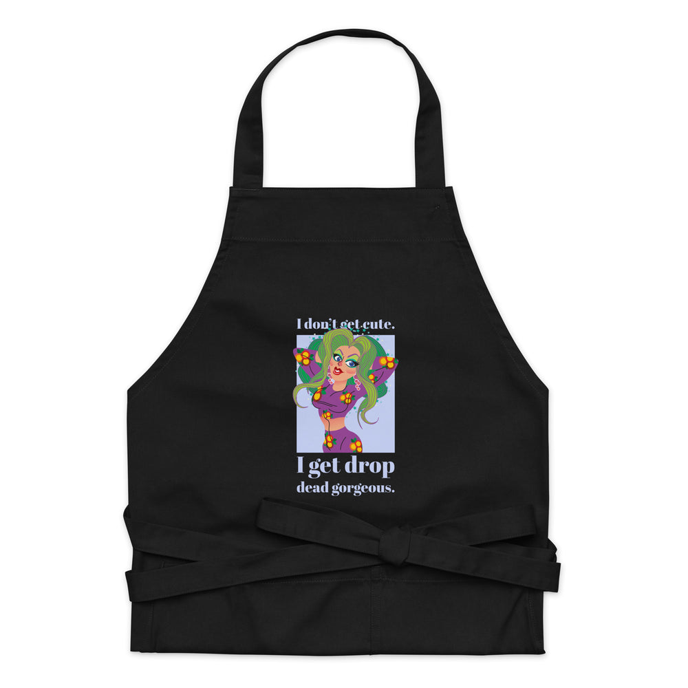 Front view of a black apron with a colorful drag-style illustration and “I don’t get cute. I get drop dead gorgeous.” text