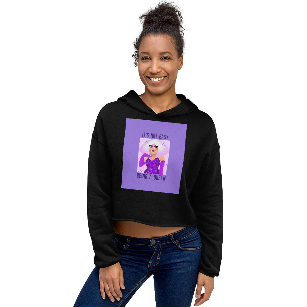 Model wearing a black cropped hoodie with purple “IT'S NOT EASY BEING A QUEEN” graphic