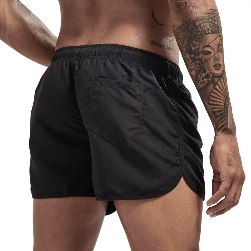 Black swim shorts shown from the back with an elastic waistband, rear pocket, and side slits