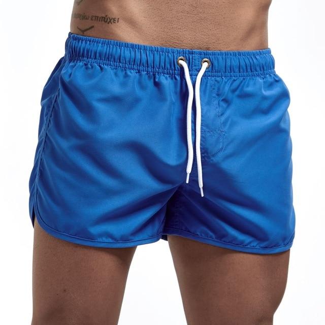 Model wearing bright blue swim shorts with a white drawstring and side pockets