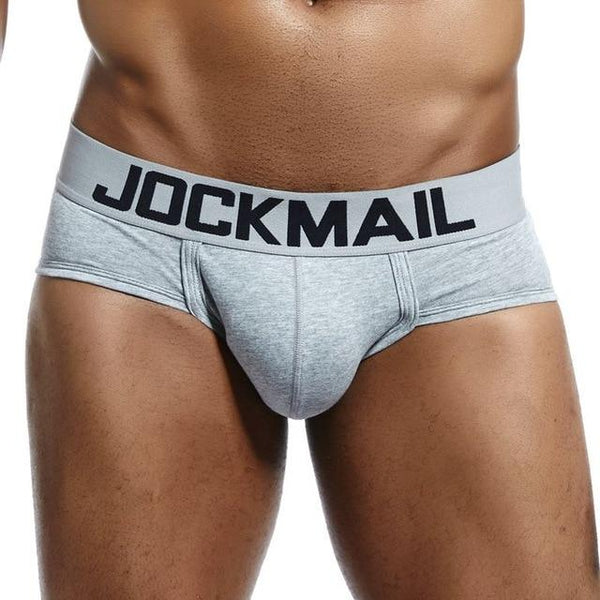 Close-up of a model wearing light gray JOCKMAIL low-rise briefs with a wide logo waistband