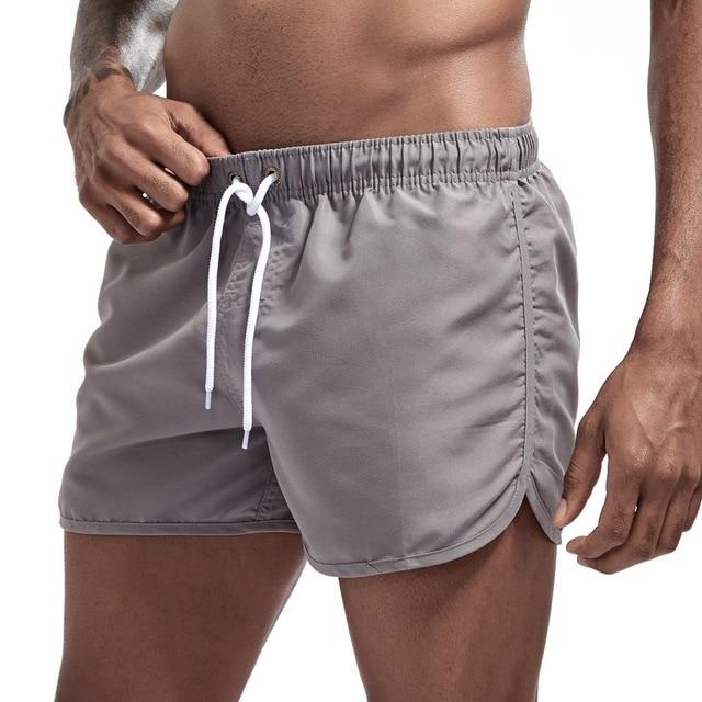 Close-up of gray swim shorts with white drawstring and curved side slits