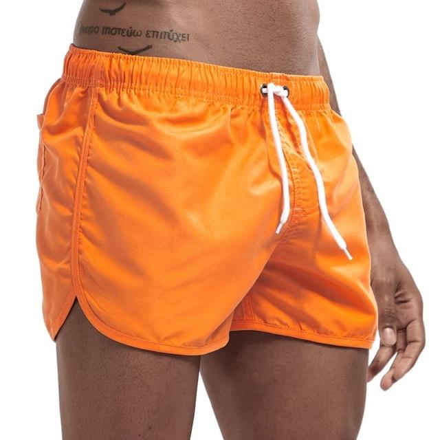 Close-up of a model wearing bright orange swim shorts with white drawstring