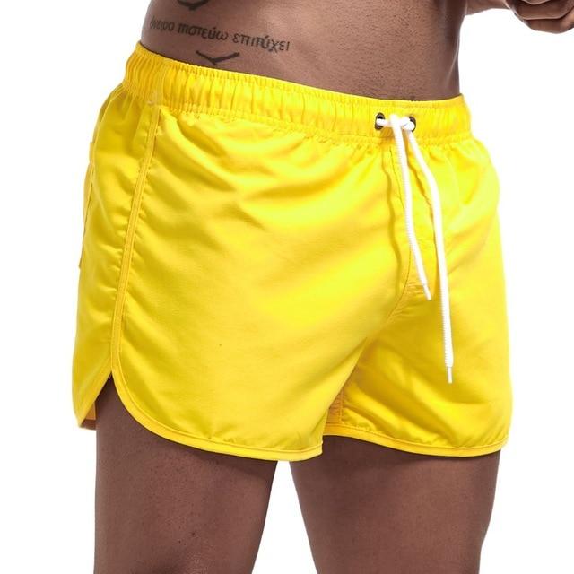 Bright yellow swim shorts with white drawstring and curved side slits