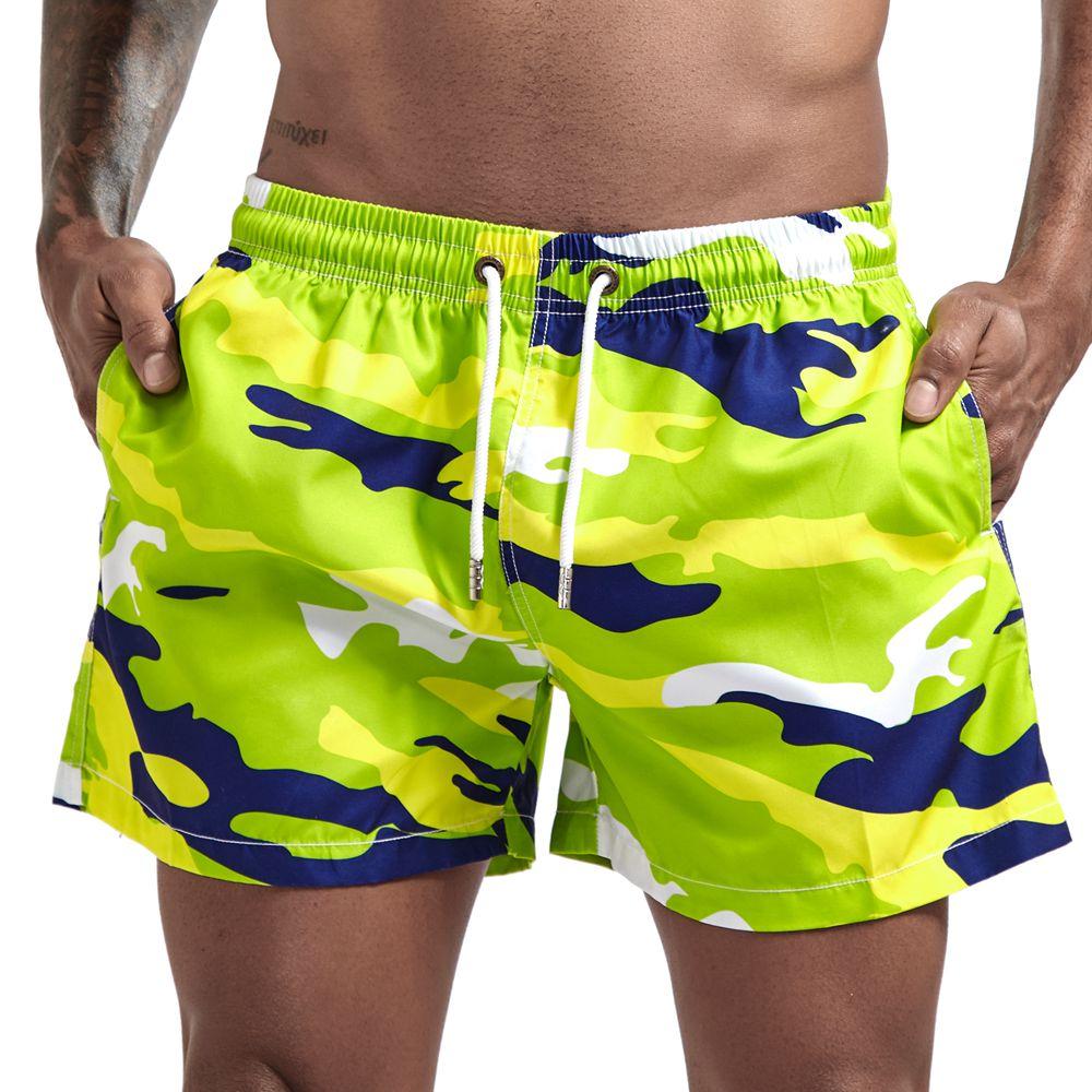 Close-up of neon green camouflage board shorts with navy, yellow, and white accents