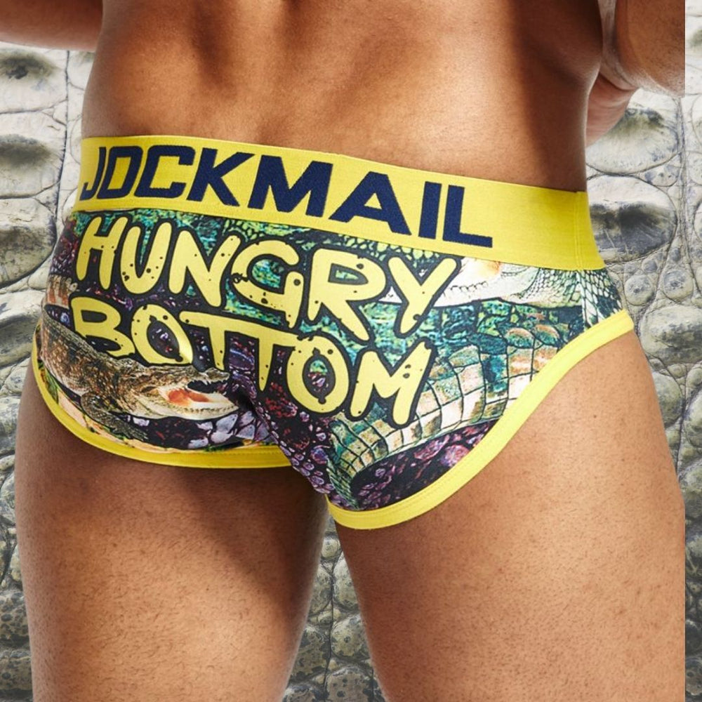 Model wearing colorful Hungry Bottom briefs with a yellow JOCKMAIL waistband and graphic print