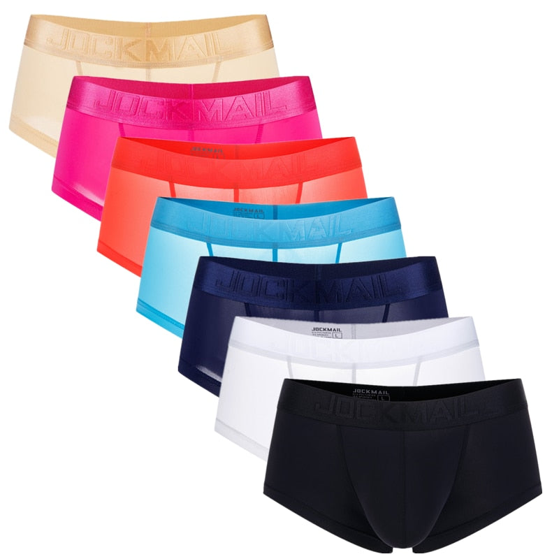 Seven Jockmail boxer briefs arranged in a fan, shown in beige, pink, coral, blue, navy, white, and black