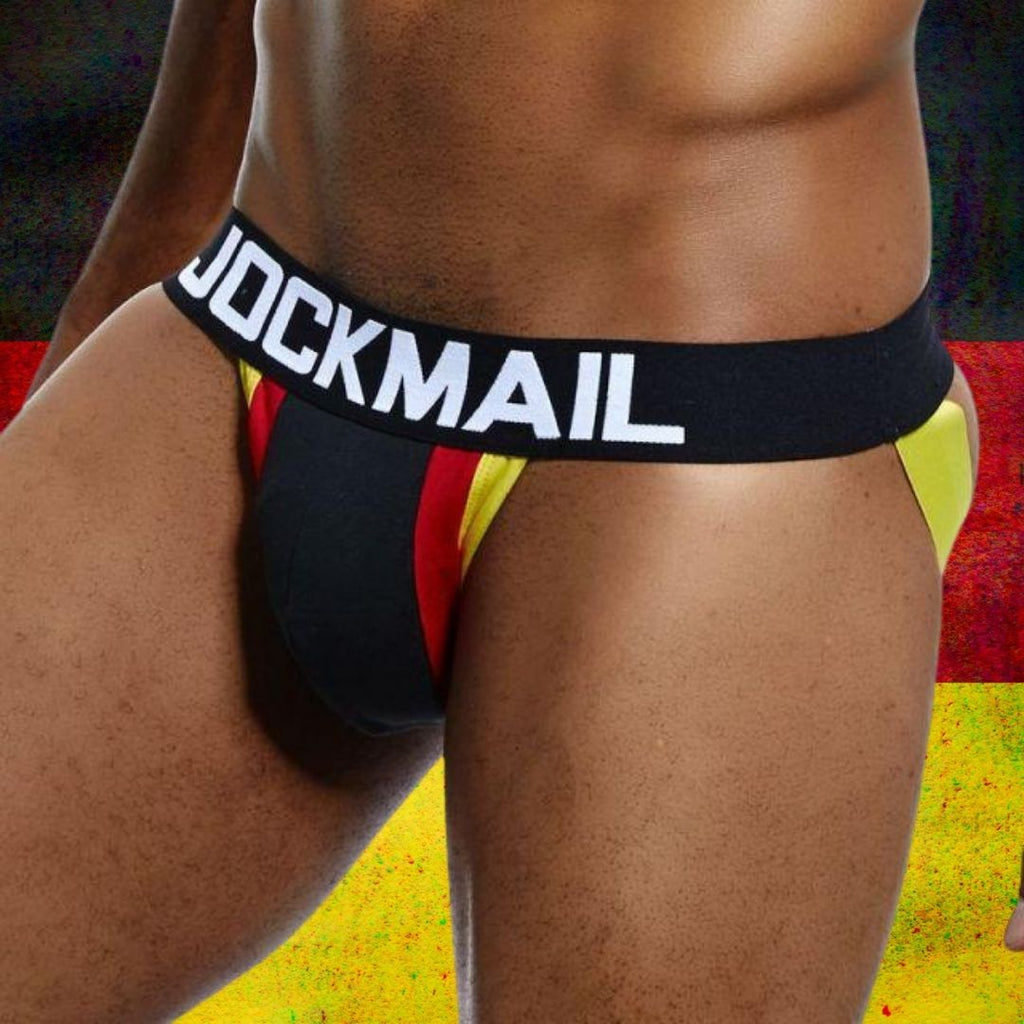 Model wearing a black jockstrap with red and yellow panels and a JOCKMAIL waistband