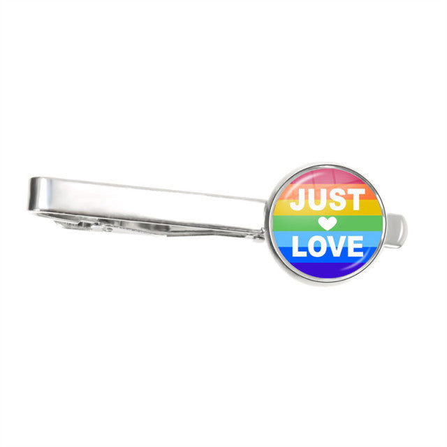 Silver tie clip with a rainbow-striped round badge reading “JUST LOVE”