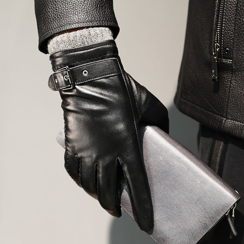 Close-up of a black leather glove with a buckle strap gripping a silver clutch