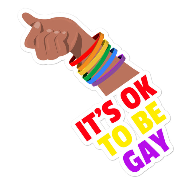 Sticker with a raised fist, rainbow bracelets, and the words “IT’S OK TO BE GAY”