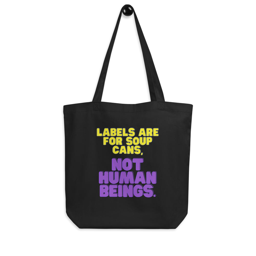 Black tote bag with yellow and purple text reading “Labels Are for Soup Cans, Not Human Beings.”