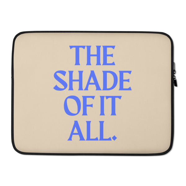 Front view of a beige laptop sleeve with black trim and blue “THE SHADE OF IT ALL” text