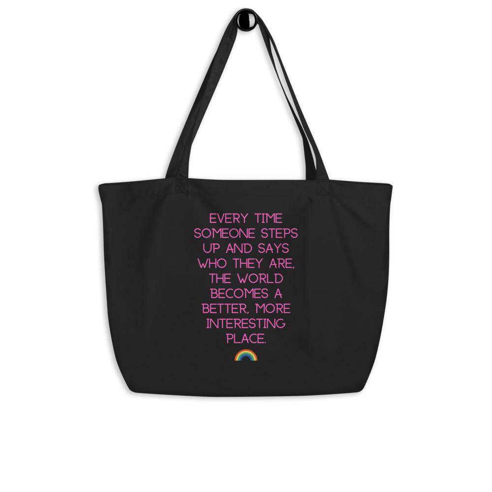 Black organic tote bag with pink text reading “Every time someone steps up…” and a rainbow icon