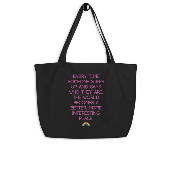Black organic tote bag with pink text reading “Every time someone steps up…” and a rainbow icon