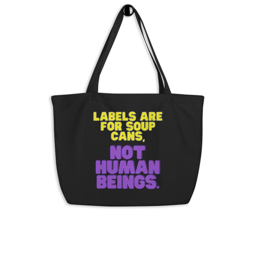 Black organic tote bag with yellow and purple text reading “Labels Are For Soup Cans, Not Human Beings.”