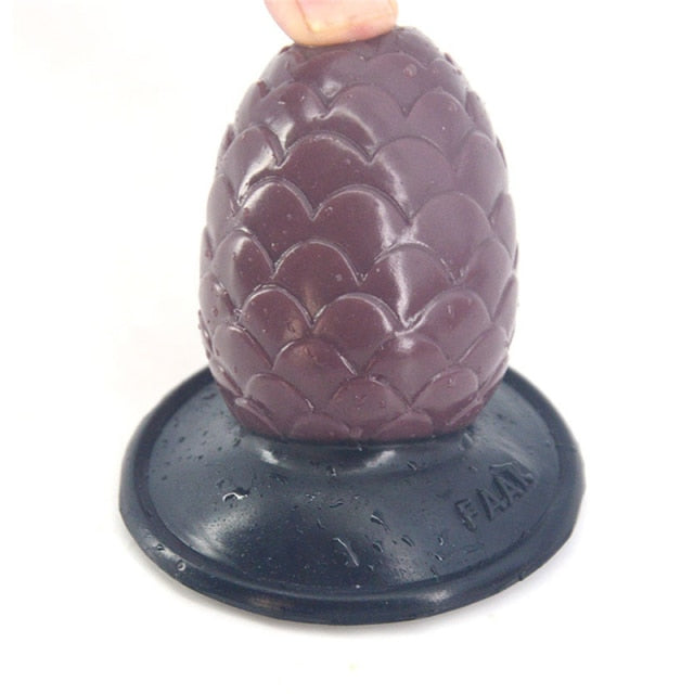 Close-up of a purple, lotus-textured anal plug with a black flared base, held at the top