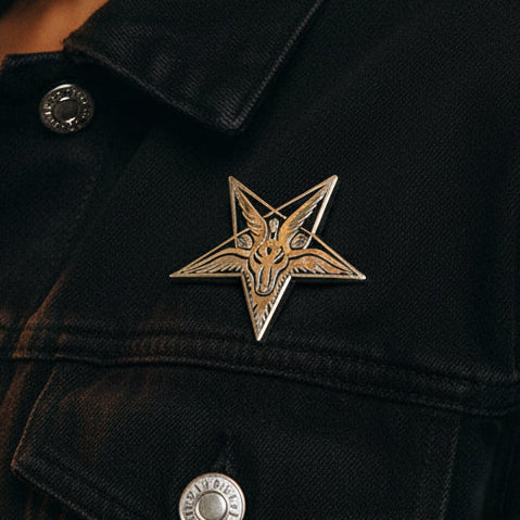 Gold-toned Lucifer enamel pin featuring a horned goat head on a black jacket
