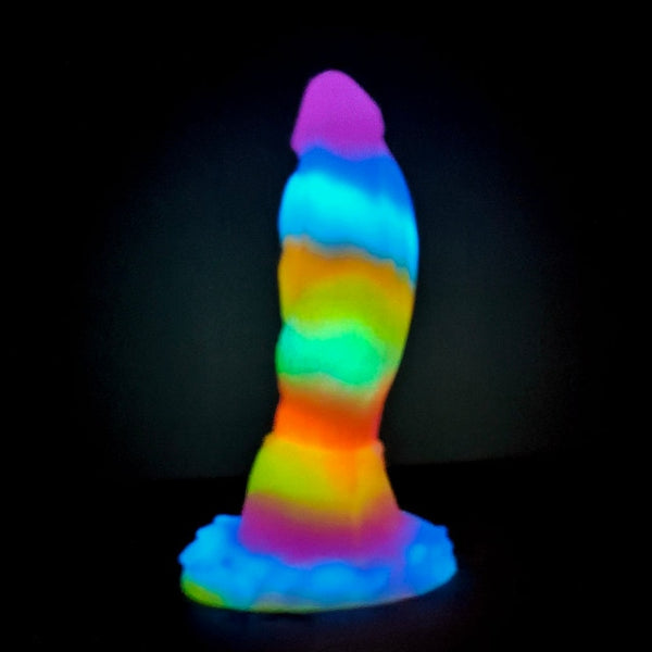 Glow-in-the-dark rainbow dragon-shaped dildo standing on a suction-cup base
