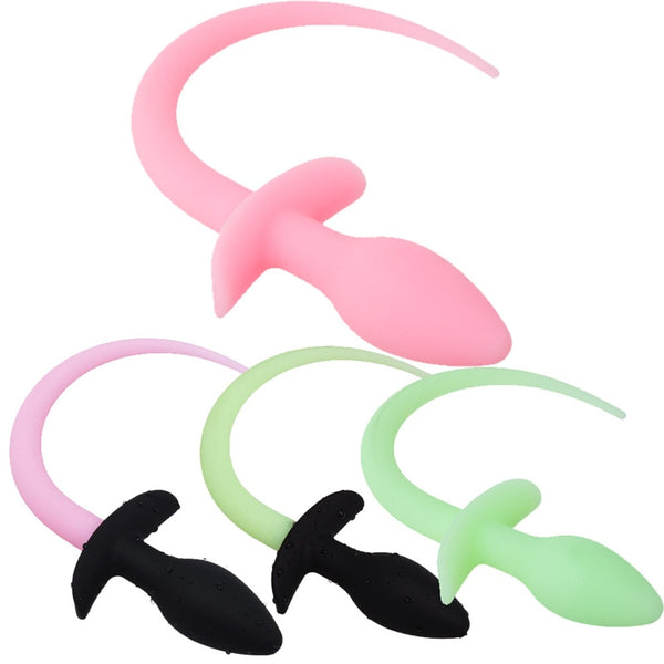 Three silicone dog-tail butt plugs in pink, black, and pale green, shown on white