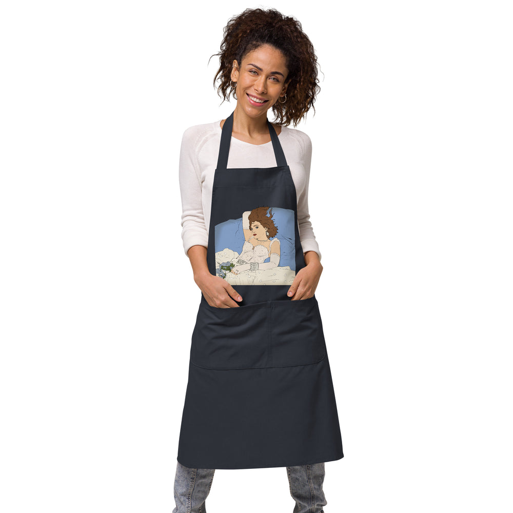 Front view of a black apron worn by a smiling model, with a vintage pin-up illustration on the bib
